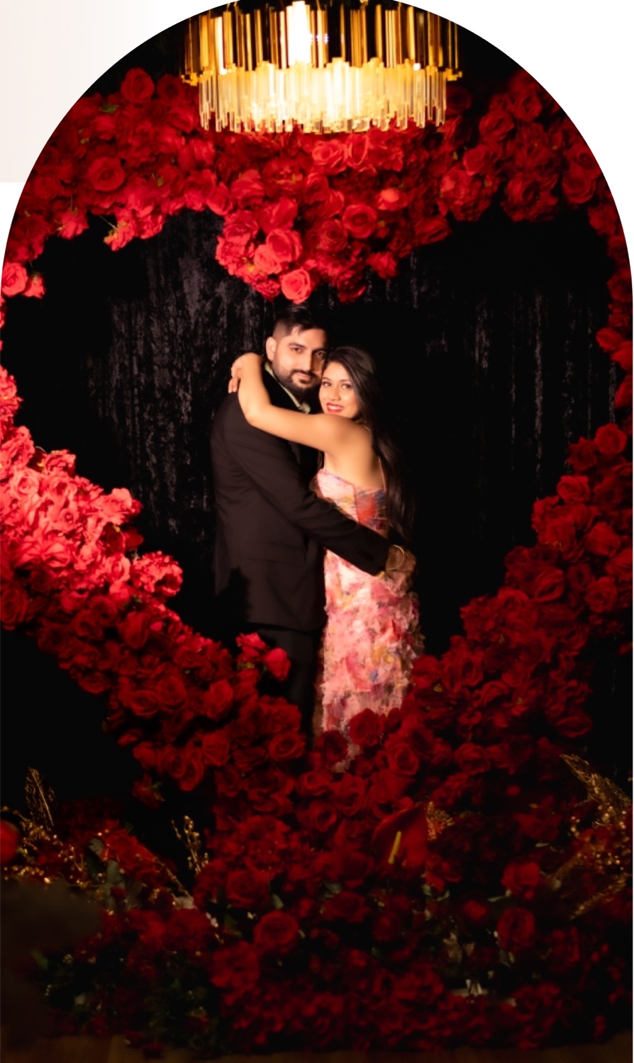 Couple embracing inside a heart of red roses beneath a gold chandelier